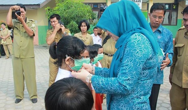 Ketua TP PKK Kota Jambi Yuliana Fasha memasang masker kepada salah satu siswa SD. F/WISMAN/JAMBIUPDATE