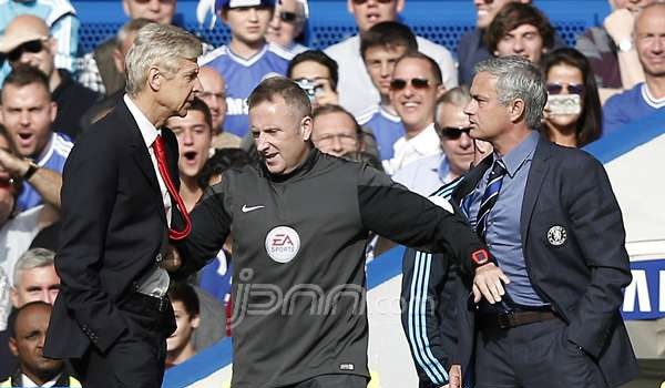 Manajer Chelsea Jose Mourinho dan Manajer Arsenal Arsene Wenger dipisahkan ofisial pertandingan Jonathan Moss, saat Chelsea berhadapan dengan Arsenal, dalam lanjutan EPL di Stamford Bridge, London, Minggu (5/10). Foto: AFP PHOTO/ADRIAN DENNIS