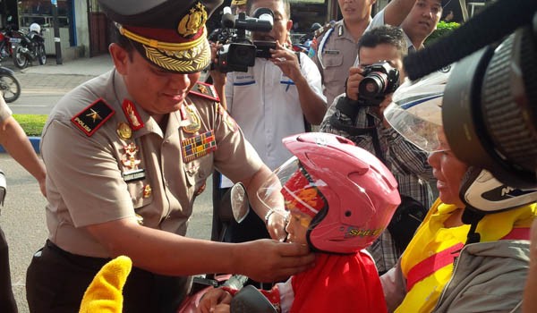 Kapolda Jambi, Brigjen Pol Bambang Sudarisman memasangkan helm kepada pengendara anak-anak