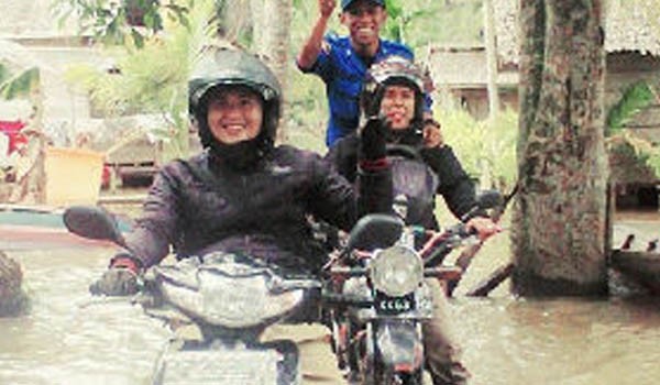 Warga yang menggunakan motor ditengah genangan air banjir