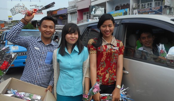 Pegawai aston yang membagi-bagikan bunga kepada pengguna jalan.