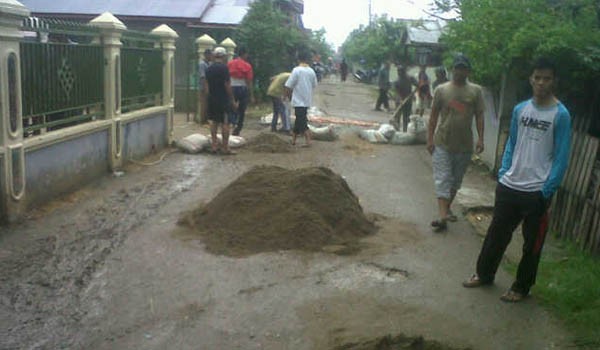 Warga saat gotong royong memperbaiki jalan
