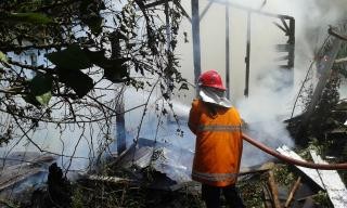 Petugas pemadam saat berusaha memadamkan api yang melalap rumah di depan RSU H Hanaffe, Bungo