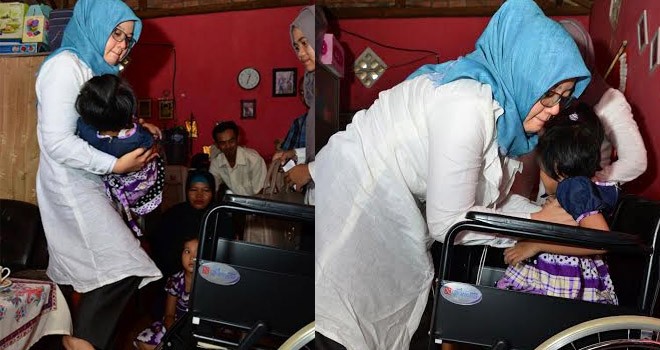 (Foto Kiri) Ketua TP-PKK Hj. Yuliana Fasha menggendong Liza. (Kanan) Ketua TP-PKK Hj. Yuliana Fasha membantu Liza duduk di kursi roda.