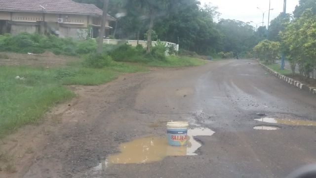 Ember cat yang diletakkan warga di tengah badan jalan yang mengalami kerusakan