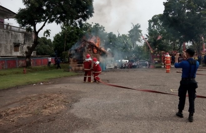 Petugas berusaha memadamkan api di sebuah rumah di depan kantor Damkar Kota Jambi