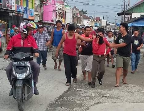 RK (baju merah lengan panjang) saat digelandang warga ke Polsek Gunung Kerinci. 