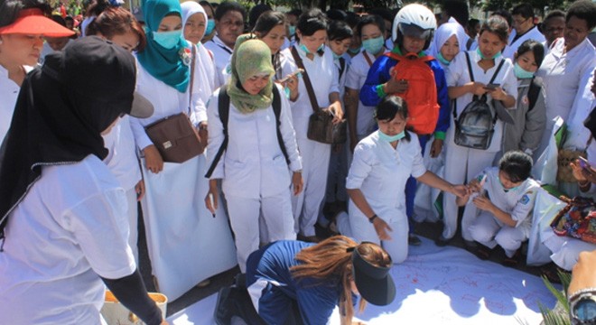 Para bidan membubuhkan tanda tangan pada kain putih sebagai tanda simpatik mereka kepada rekannya yang menjadi korban kasus percobaan pemerkosaan.