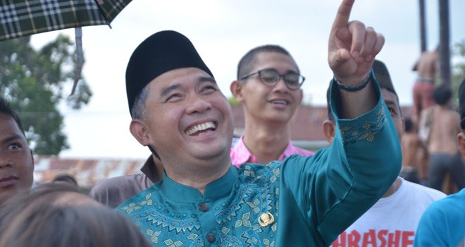 Walikota Fasha terpingkal-pingkal dan menunjuk salah satu pohon pinang yang sedang dipanjat peserta lomba.