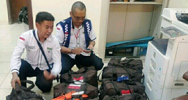 Petugas saat memeriksa barang bawaan jamaah saat berada di bandara.