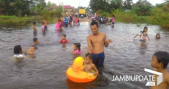 Terlihat keseruan anak-anak mandi di lokasi banjir yang menggenangi jalan.