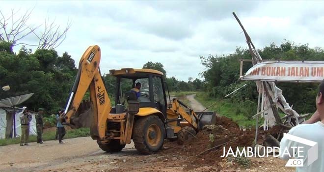 Terlihat alat berat sedang bongkar pemblokiran jalan oleh warga.