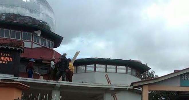 Terlihat warga membersihkan puing-puing kubah mas yang terkena angin.