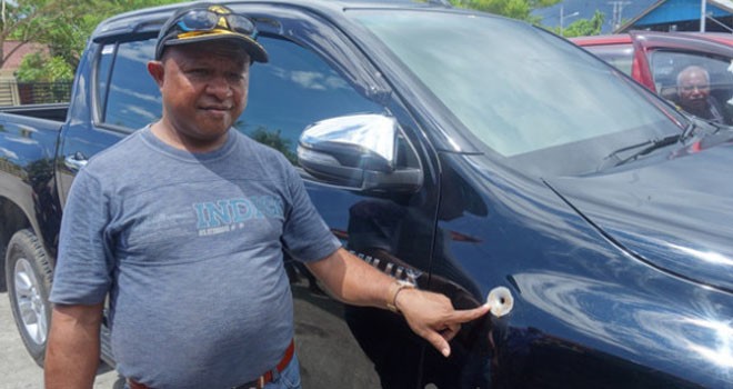 Hendrison Ondi menunjukkan bekas tembakan di mobil dinasnya. Foto: Cenderawasih Pos