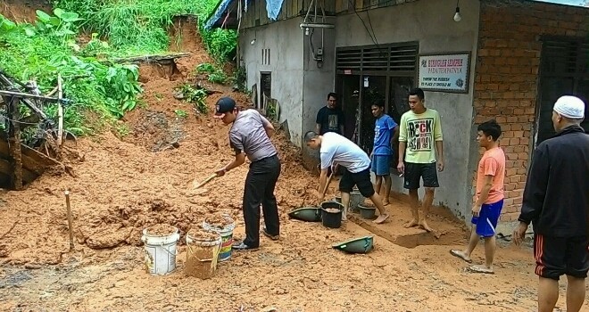 Terlihat aparat kepolisian membersihkan lumpuran tanah yang menimbun rumah warga akibat hujan deras yang mengguyur Merangin.