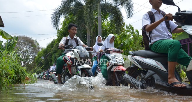 Terlihat siswa mengendarai sepeda motor di tengah-tengah banjir untuk pergi ke sekolah. Foto: MRIDWAN/JE