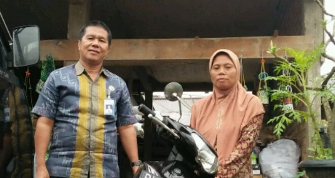 Leni Haini, salah satu mantan atlet dayung berprestasi  menggunakan motor bantuan Jasa Raharja unutk operasional usaha bank sampahnya.