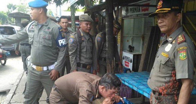 Kabid Trantibmas Satpol PP Kampar, Ahmad Zaki membersihkan wajahnya yang terkena cabe usai dilempari pemilik rumah makan yang terkena razia. Foto: JPG