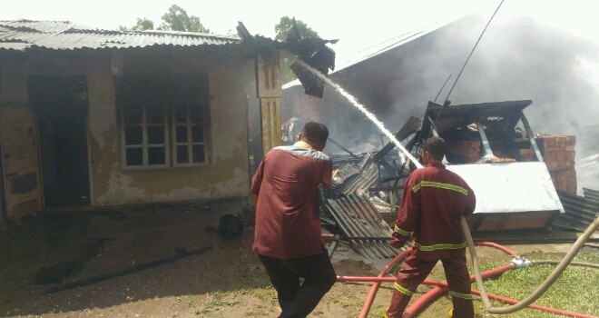 Tampak petugas berusaha memadamkan api yang membakar rumah warga.