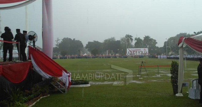 Penurunan bendera merah putih di lapangan Kantor Gubernur Jambi diguyur hujan.