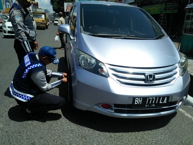 Petugas Dishub Kota Jambi gembok mobil yang parkir sembarang.