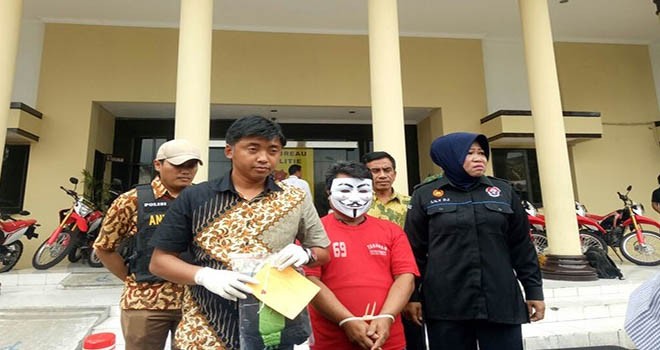 Tersangka predator anak MDK (memakai topeng) saat berada di Mapolrestabes Surabaya, Jumat (8/12). Foto Dida Tenola/JawaPos.com)
