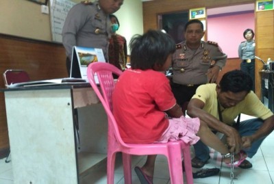 Ahli kunci saat berusaha membuka rantai yang melilit kaki bocah 11 tahun yang diduga koran eksploitasi ayah tirinya, Jumat (12/1). (Riki Chandra/JawaPos.com)