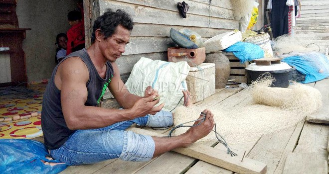 Tampak nelayan yang mengambil upah jahit jaring sebelum menangkap ikan.