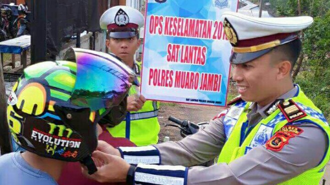 Kasat Lantas Polres Muaro Jambi AKP A. Aziz Sholahudin saat memasang helm salah seorang pengendara motor 