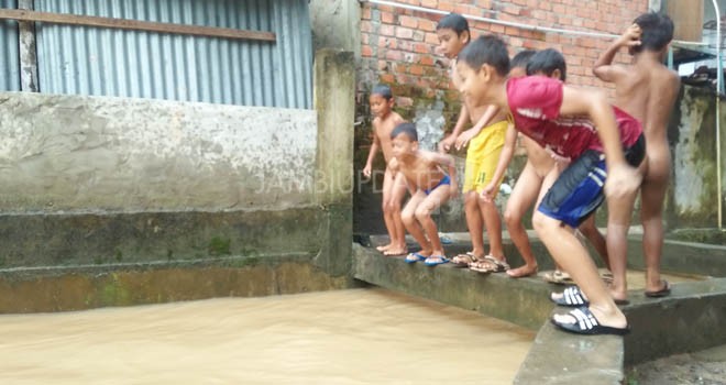Luapan air hujan di drainase yang melintasi Perumahan Namura Indah III menjadi kolam renang dadakan bagi anak-anak sekitar. 