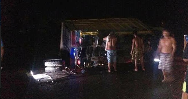 Warga saat mendatangi lokasi kejadian, Kamis malam. Terlihat Kondisi mobil truk yang terguling ke sisi kiri.        