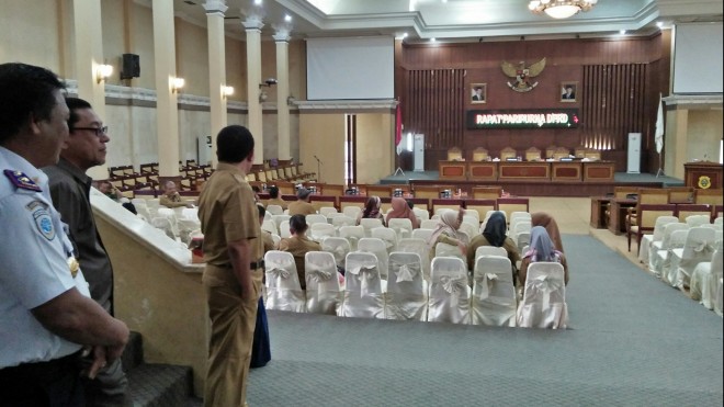 Tampak sekda sedang berdiri melihat kursi ruang sidang masih banyak kosong. 