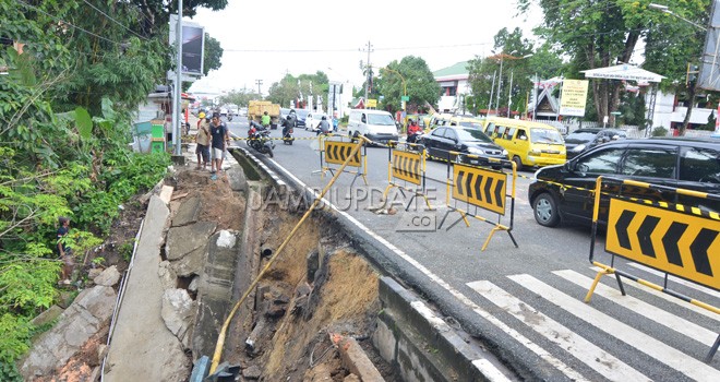 Jalan longsor di kawasan TAC Kota Jambi sudah tiga bulan dibiarkan. Belum ada tanda-tanda perbaikan.