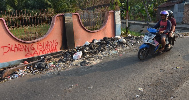 Warga membuang sampah di luar TPS, akibatnya sampah berserakan ke badan jalan dan dikeluhkan warga.
