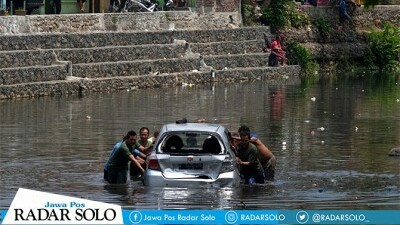 Warga mendorong mobil yang nyebur ke Sungai Banjaran Bantarsoka, Purwokerto, Senin (8/10) pagi. (RADAR BANYUMAS)