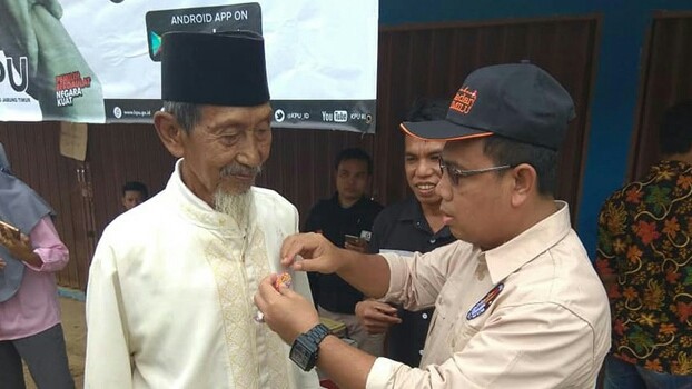 PEMILIH : Komisioner KPU Provinsi Jambi, M. Sanusi memasangkan pin GMHP kepada salah satu warga Tanjabtim pada segerak cek pemilih serentak, Rabu (17/10) kemarin.