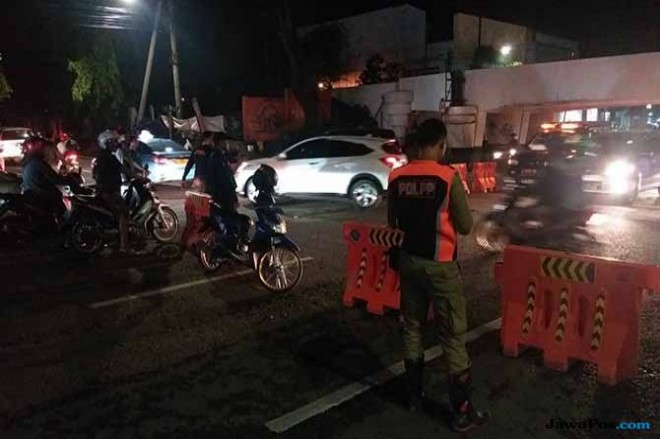 Petugas menutup akses Jalan Sulawesi, dekat viaduk Kertajaya, Selasa (18/12) malam. (Dida Tenola/JawaPos.com)