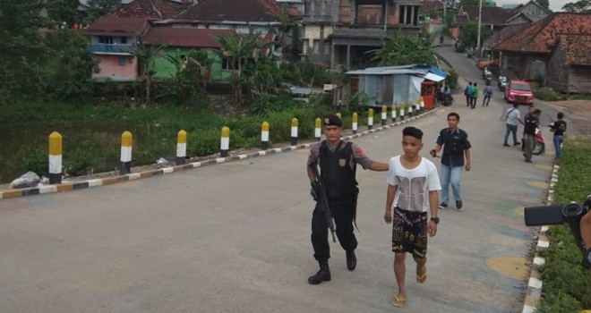 Salah seorang pria saat digiring oleh petugas bersenjata laras panjang ketika razia di Pulau Pandan, Kecamatan Danau Sipin, Kota Jambi, Selasa (19/2). Foto : Ist