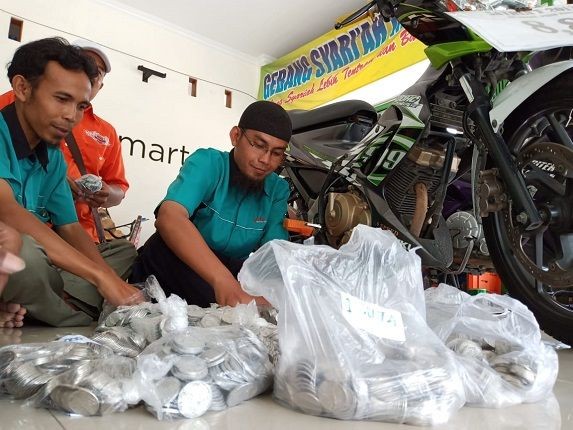 UANG RECEH: Nur Komaini dan juga karyawan tengah menghitung uang receh dari Eksan Widodo, Sabtu (9/3). (Ari Purnomo/JawaPos.com)