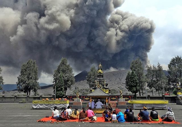 TETAP BERAKTIVITAS: Sejumlah warga Tengger tetap beribadah di Pura Luhur Poten yang ada di lautan pasir Bromo, Rabu (20/3), meski abu vulkanik membumbung dari kawah Bromo. (Zainal Arifin/Jawa Pos Radar Bromo)