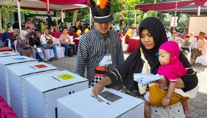 Salah satu petugas KPPS memastikan seorang ibu memasukkan surat suara di kotak yang benar pada simulasi nasional Pemilu 2019.