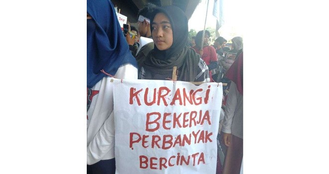 Spanduk Aksi Bertulis â€œKurangi Bekerja Perbanyak Bercintaâ€