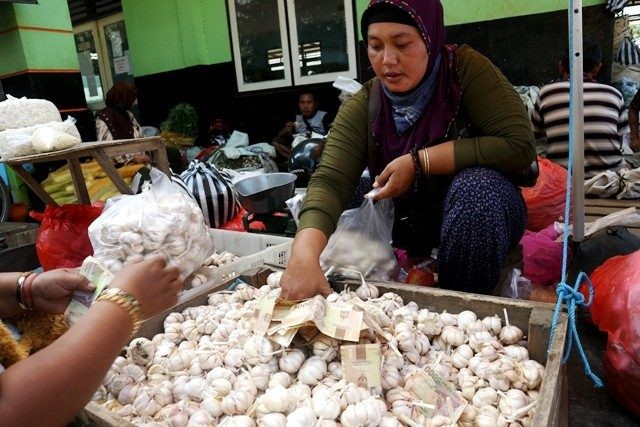 Ilustrasi pedagang menjual bawang putih kepada seorang ibu. Kementerian Perdagangan akan menambah pasokan untuk menekan harga bawang putih (Radar Kediri/JPG)