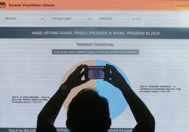 Pekerja memotret layar rekapitulasi penghitungan suara melalui aplikasi Situng di Kantor Komisi Pemilihan Umum (KPU), Jakarta, Sabtu (20/4). Saat ini rekapitulasi penghitungan suara melalui aplikasi Situng masih terus berjalan, KPU menegaskan Situng hanya merupakan informasi dan tidak akan mempengaruhi penetapan hasil pemilu 2019 karena rekapitulasi resmi tetap dilakukan secara manual. (MIFTAHULHAYAT/JAWA POS)