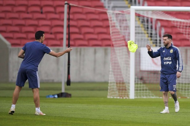 Pelatih Argentina, Lionel Scaloni melemparkan rompi kepada Lionel Messi. (Foto: Carl DE SOUZA / AFP)