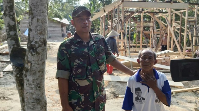Babinsa Koramil 415-04/Muara Bulian Serda Tri Purwanto membantu warga gotong royong membangun rumah Rito (70) di RT 12 Desa Ladang Peris. 