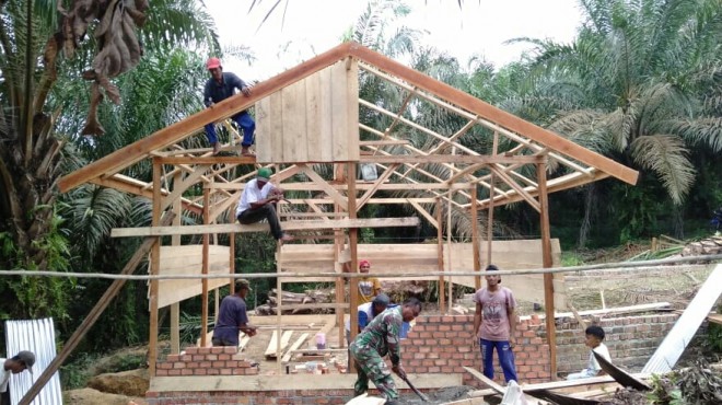 Babinsa Koramil 415-14/Muara Bulian, Sertu Muharamaini melakukan gotong royong bersama warga sekitar membangun rumah Heri Sarifudi (36) RT 06 Desa Ladang Peris.