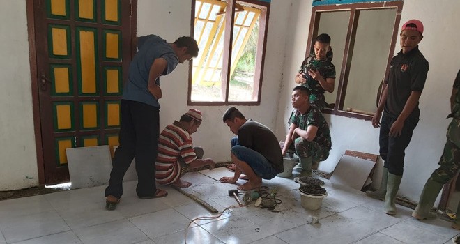 Satgas TMMD Gotong Royong Bersama Warga Pasang Keramik Musholla Baitul Mukmin.