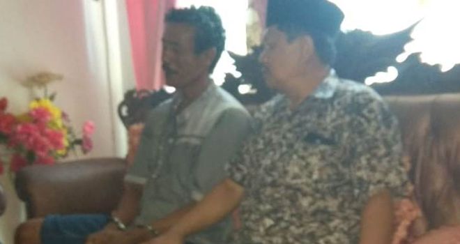 Hamzah (diborgol) saat diamankan di rumah Kades Simbur Naik, yang dijaga ketat oleh pihak Kepolisian.