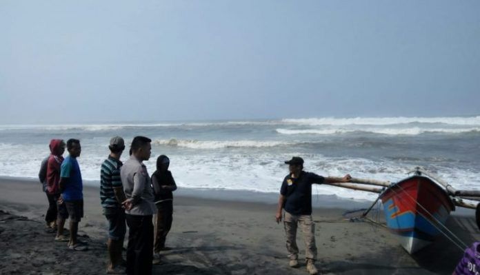 MEMANTAU: Petugas kepolisian dan warga sekitar berjaga di pesisir pantai untuk memantau dua nelayan yang masih belum ditemukan. 